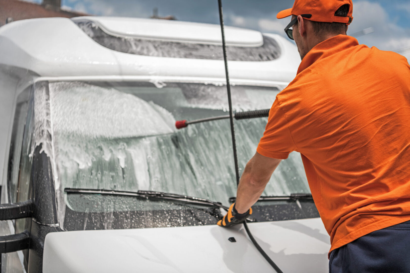 Man washing van windshield with pressure washer