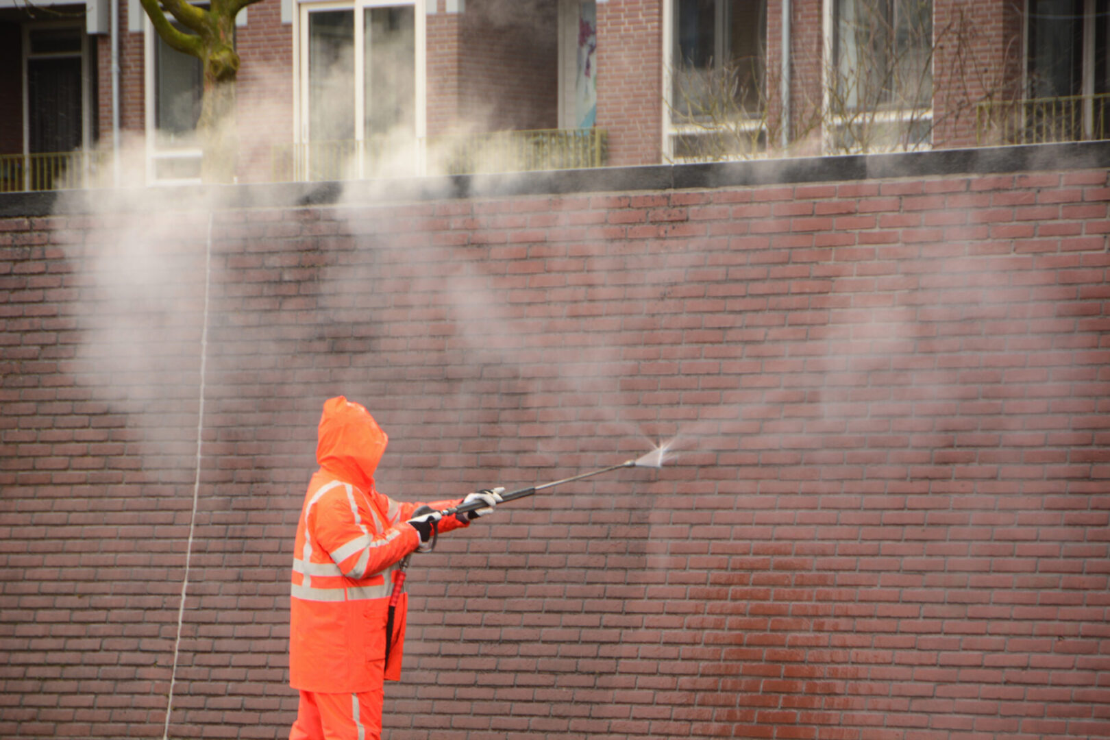 Worker pressure washing brick wall