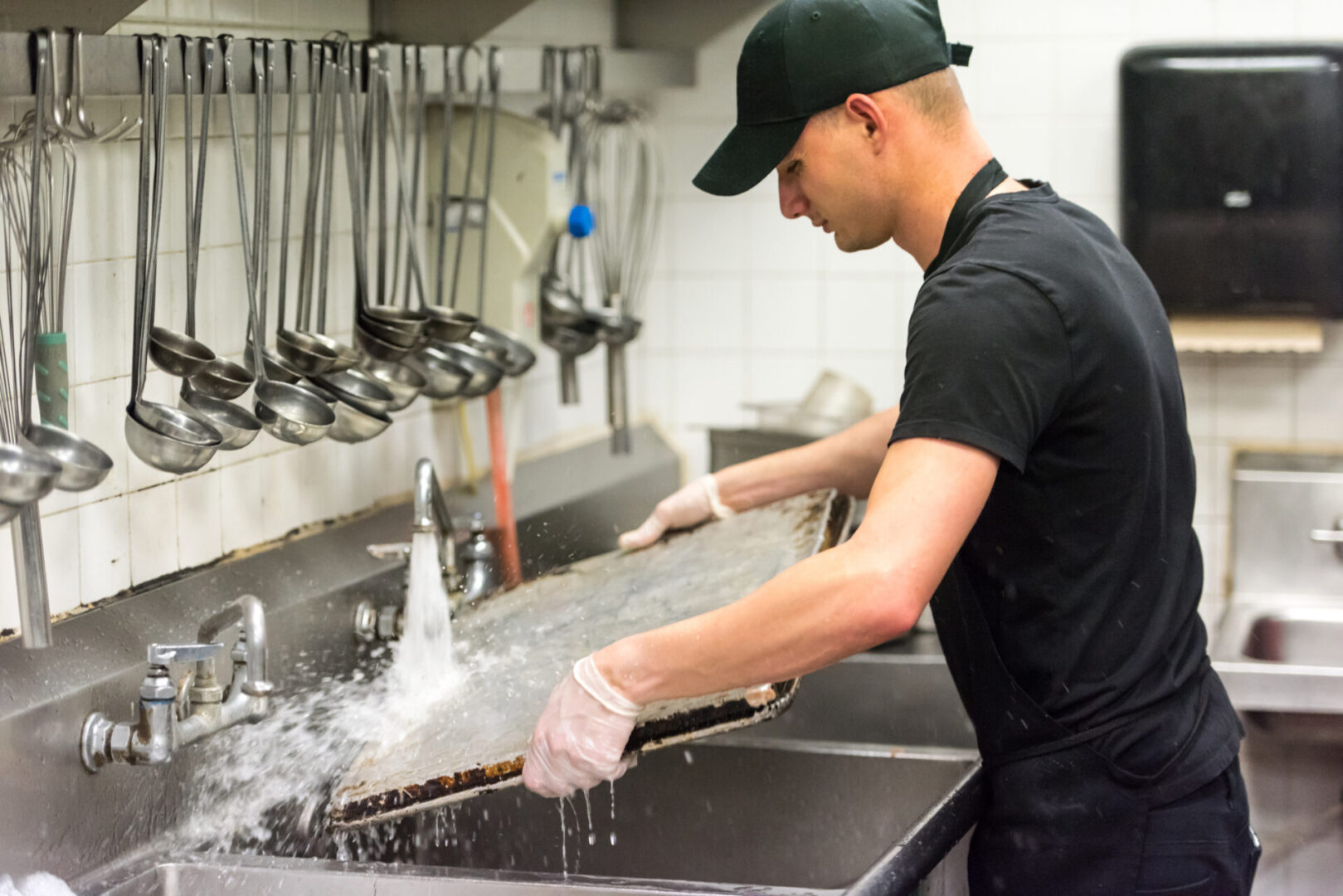 Man washing large tray in commercial kitchen