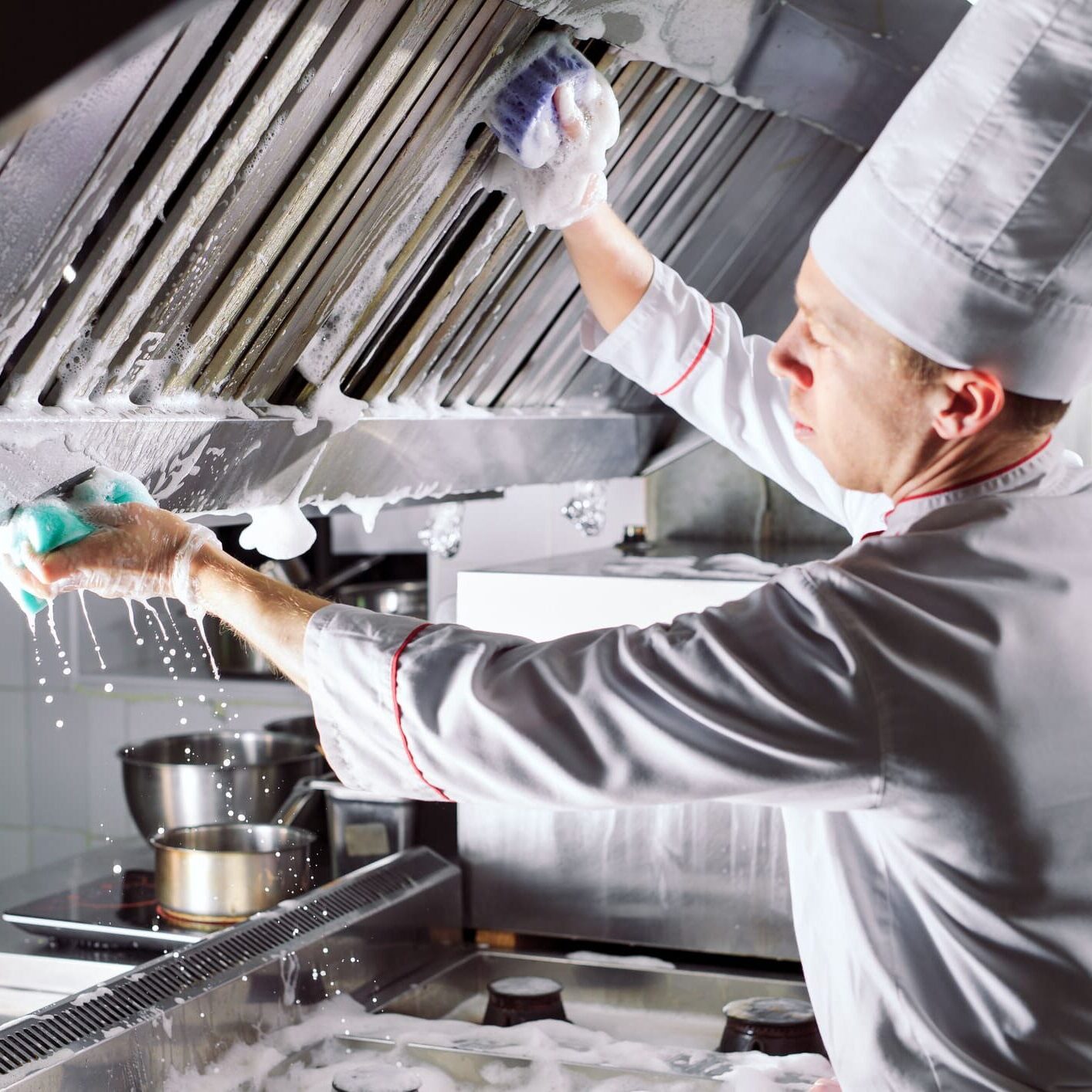 Chef cleaning commercial kitchen exhaust hood