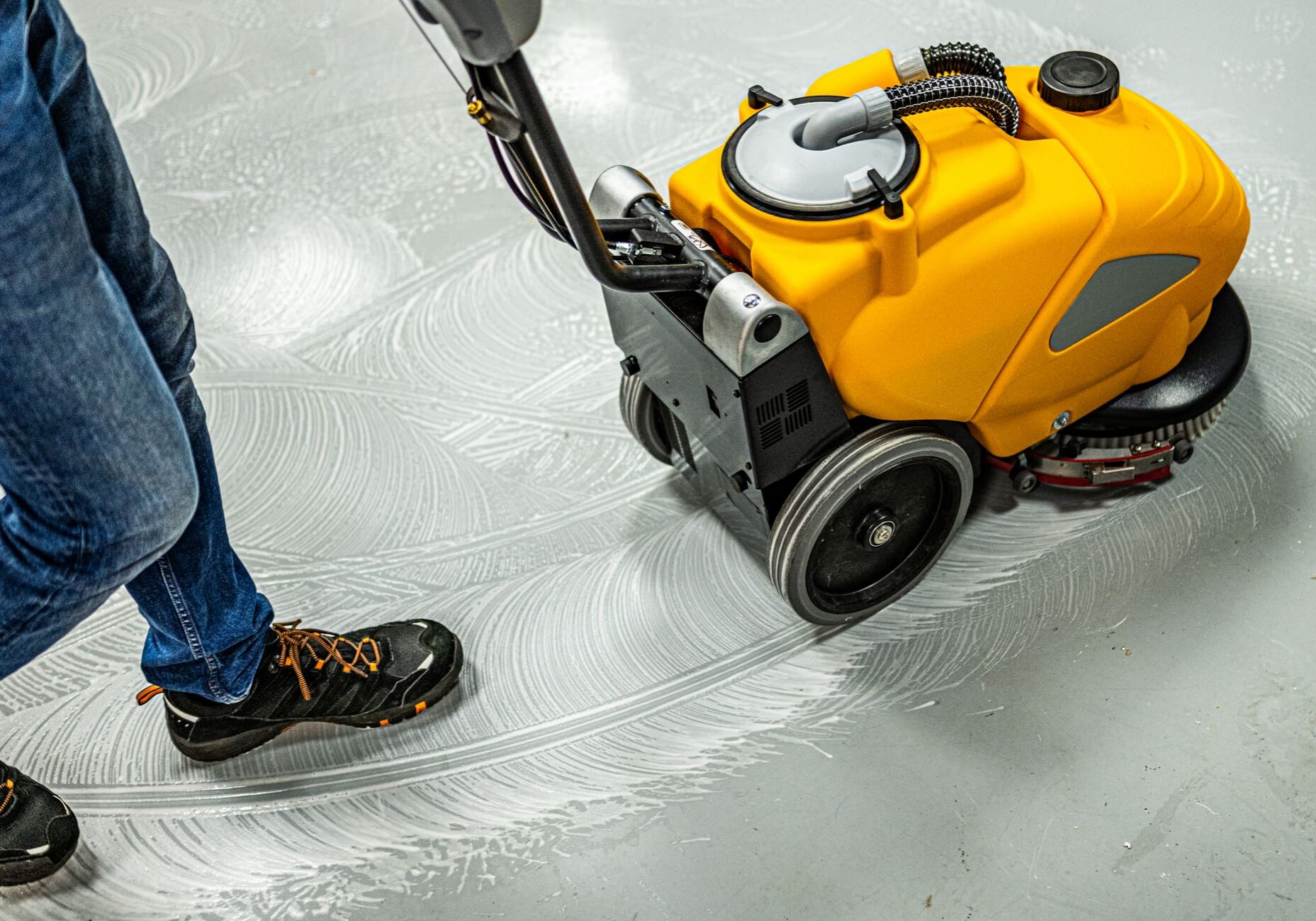 Person operating yellow floor scrubber machine